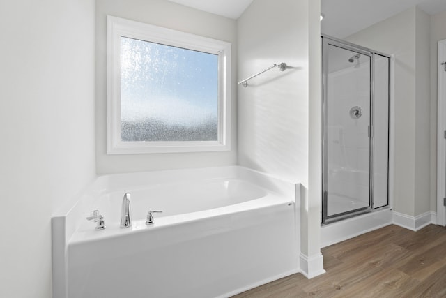 full bathroom with a garden tub, a shower stall, baseboards, and wood finished floors