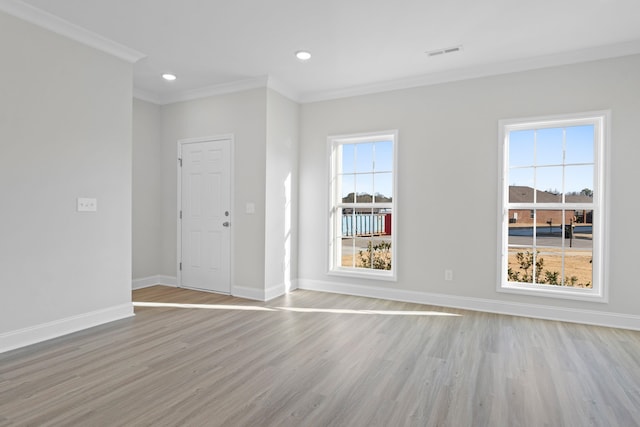 empty room featuring light wood finished floors, ornamental molding, visible vents, and baseboards