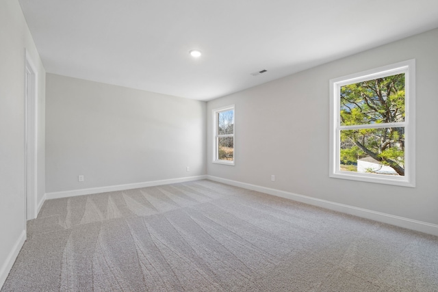 spare room with visible vents, light carpet, and baseboards