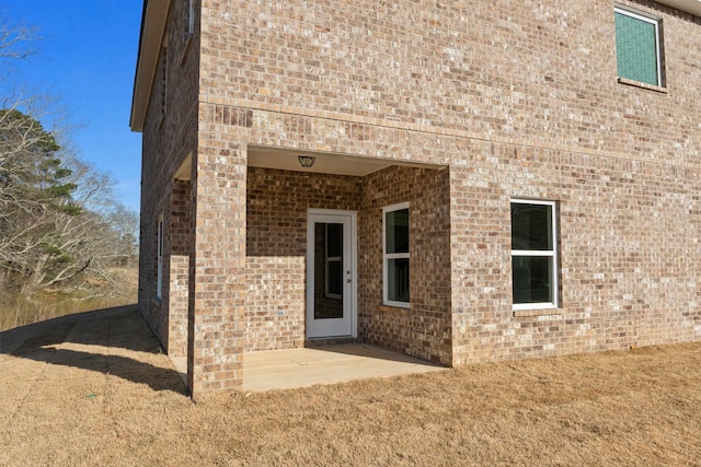 doorway to property featuring a patio area and brick siding