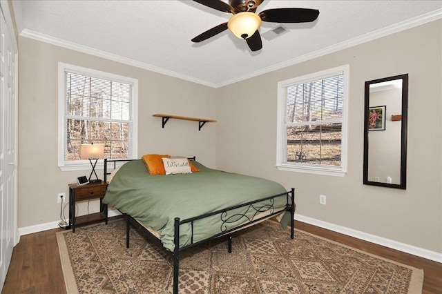 bedroom featuring dark wood-style floors, visible vents, ornamental molding, and baseboards