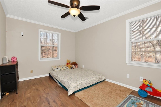 bedroom featuring crown molding, a textured ceiling, baseboards, and wood finished floors