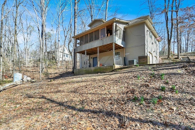 back of house with a garage, a sunroom, and central AC unit