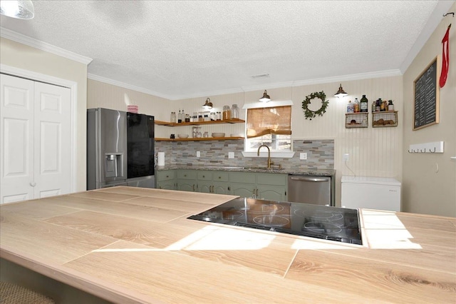 kitchen featuring a textured ceiling, ornamental molding, stainless steel appliances, and a sink