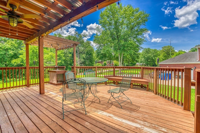  - deck featuring a pergola, ceiling fan, outdoor dining area, and view of scattered trees