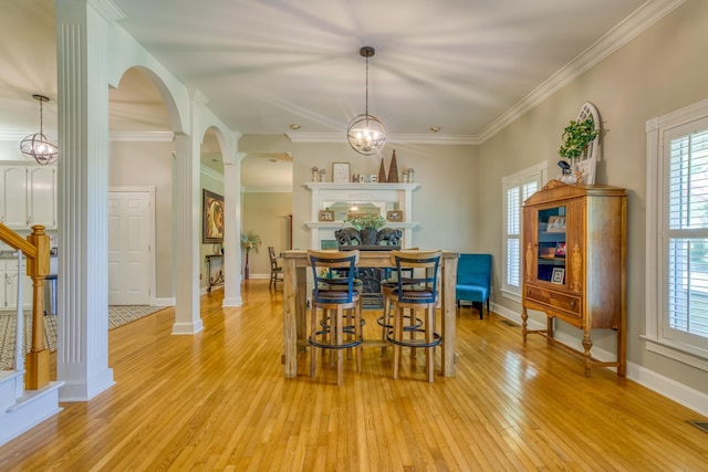  - dining room with arched walkways, light wood-type flooring, ornate columns, ornamental molding, and stairway