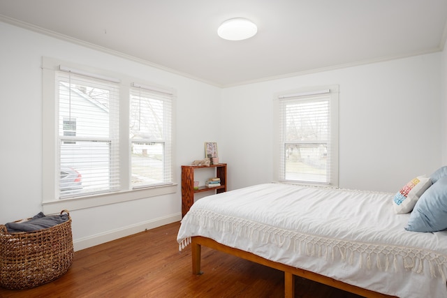 bedroom featuring ornamental molding, baseboards, and wood finished floors