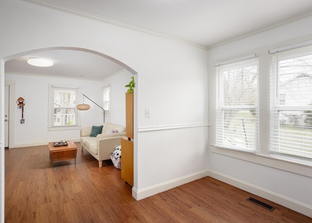 interior space with arched walkways, visible vents, ornamental molding, wood finished floors, and baseboards