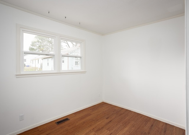 unfurnished room with ornamental molding, visible vents, baseboards, and wood finished floors