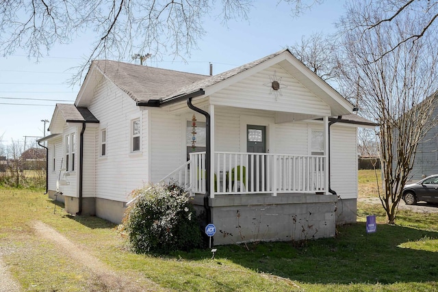 bungalow featuring a front yard, covered porch, and roof with shingles