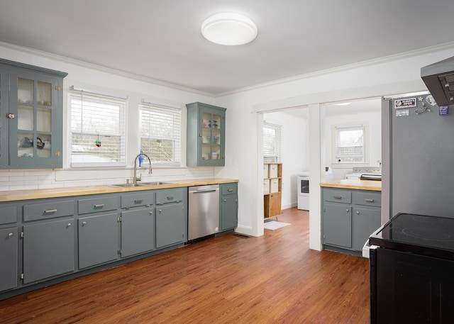 kitchen with appliances with stainless steel finishes, dark wood finished floors, a wealth of natural light, and ornamental molding