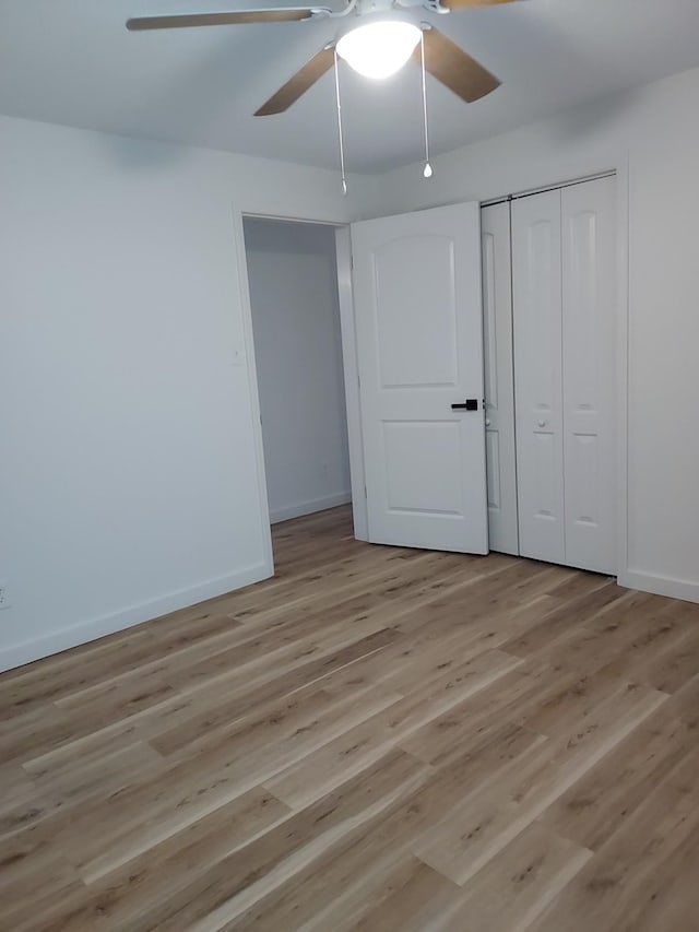 unfurnished bedroom featuring ceiling fan, a closet, and light wood-type flooring