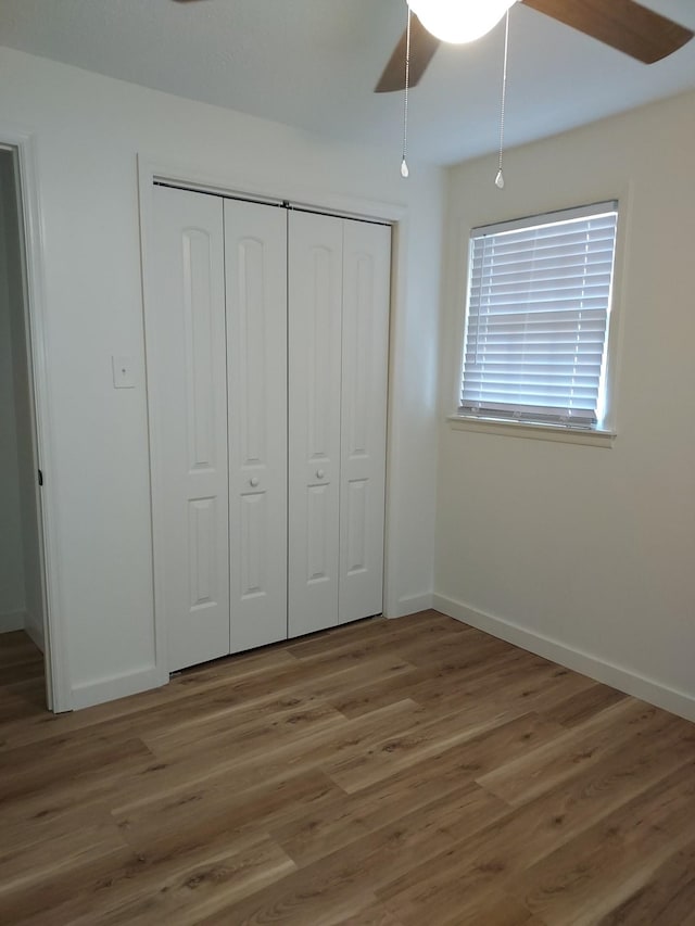 unfurnished bedroom with ceiling fan, wood-type flooring, and a closet