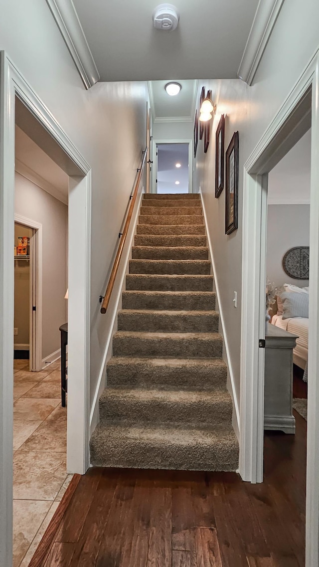 staircase featuring crown molding, baseboards, and wood finished floors