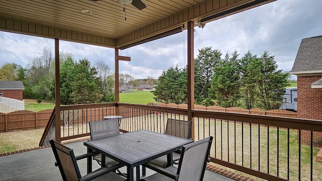 wooden terrace with a fenced backyard, a lawn, ceiling fan, and outdoor dining space