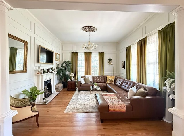  - living area with a decorative wall, a chandelier, light wood-style floors, a fireplace, and crown molding