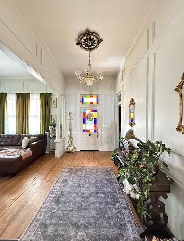  - entryway with a decorative wall, a chandelier, light wood-style floors, and ornamental molding