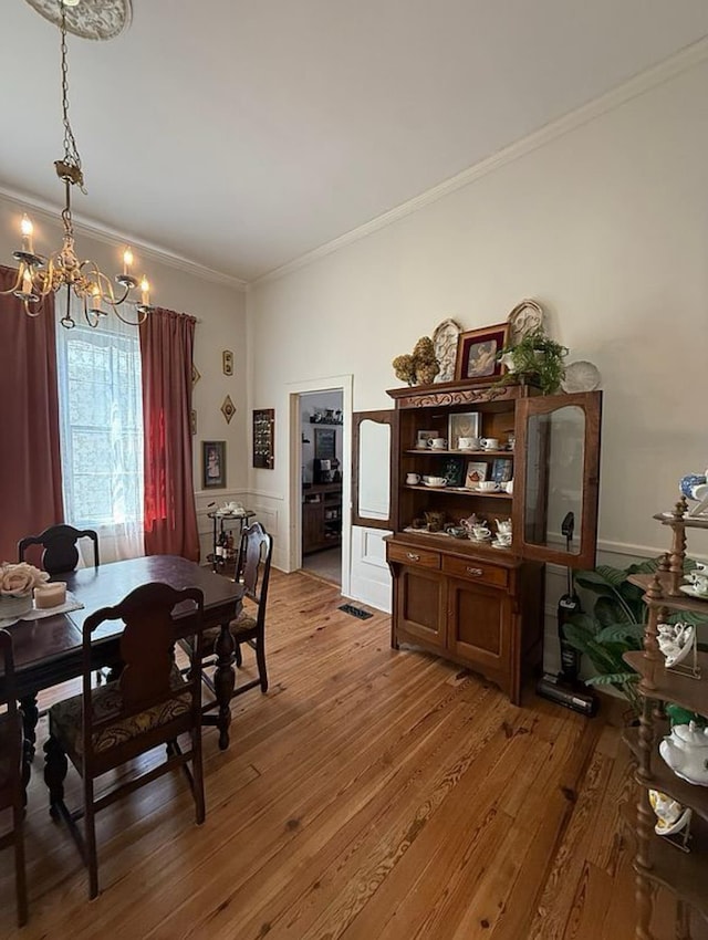  - dining area featuring a chandelier, crown molding, and light wood-type flooring