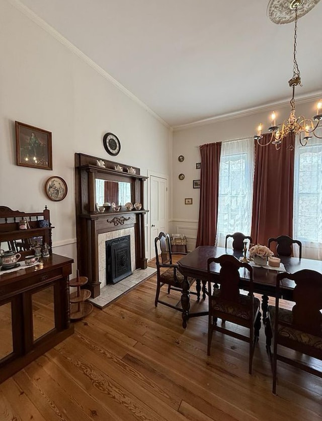  - dining area with ornamental molding, a chandelier, wood-type flooring, and a tiled fireplace