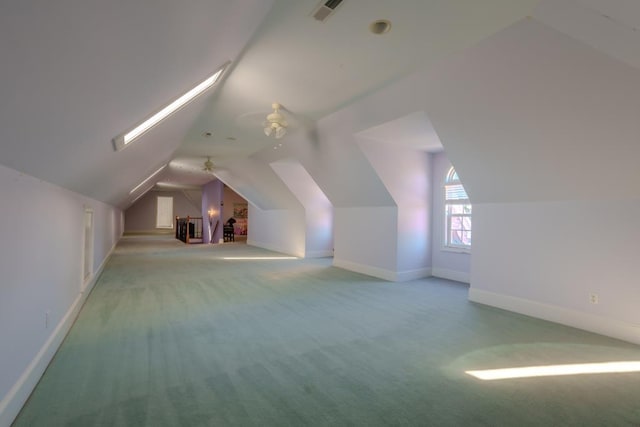 additional living space featuring vaulted ceiling with skylight, ceiling fan, and carpet floors