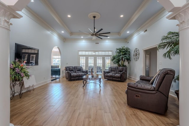 living room featuring a high ceiling, french doors, a raised ceiling, light hardwood / wood-style flooring, and ceiling fan