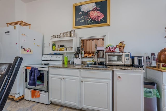 kitchen with dark stone counters, white appliances, sink, light tile patterned floors, and white cabinetry