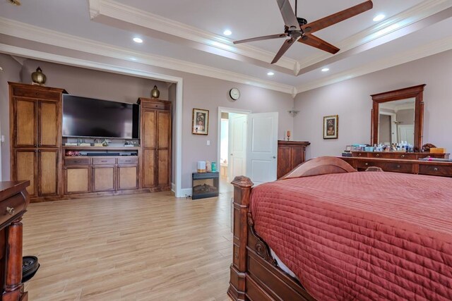 bedroom with a tray ceiling, ceiling fan, crown molding, and light wood-type flooring