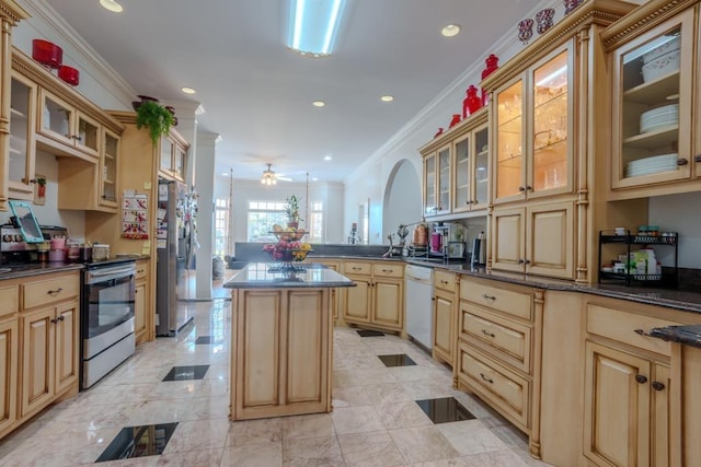 kitchen featuring kitchen peninsula, appliances with stainless steel finishes, ornamental molding, ceiling fan, and a kitchen island