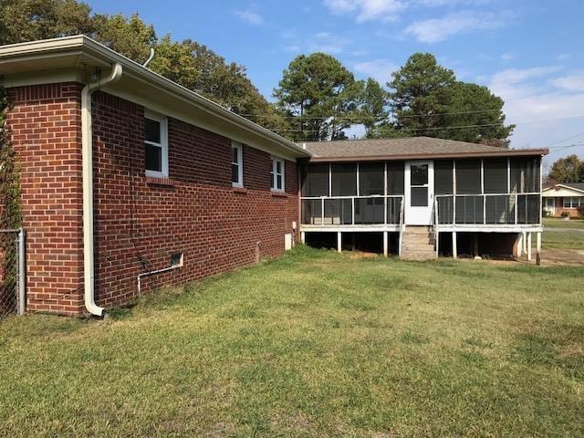 rear view of property with a sunroom and a yard