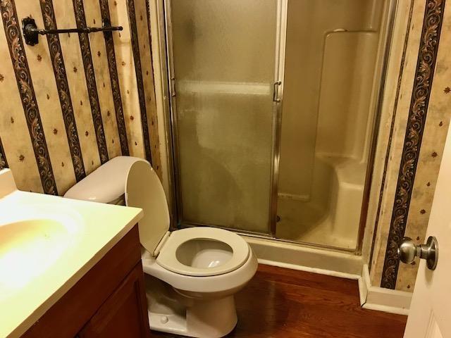 bathroom with toilet, vanity, a shower with shower door, and hardwood / wood-style flooring