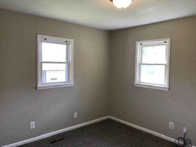 spare room with dark carpet