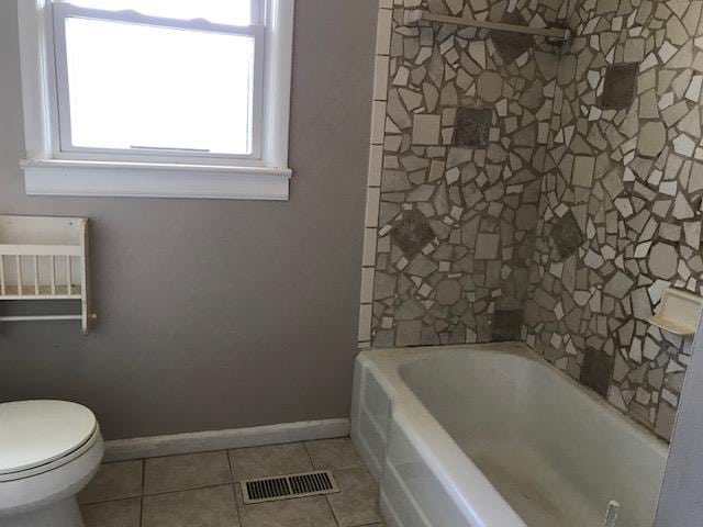 bathroom with tile patterned floors, a bath, and toilet