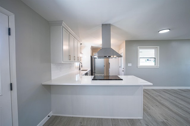 kitchen with backsplash, island range hood, kitchen peninsula, and black electric stovetop