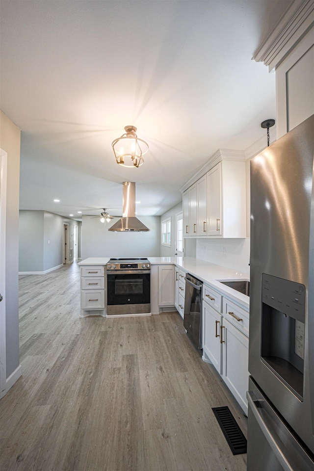 kitchen featuring white cabinetry, tasteful backsplash, island exhaust hood, and appliances with stainless steel finishes