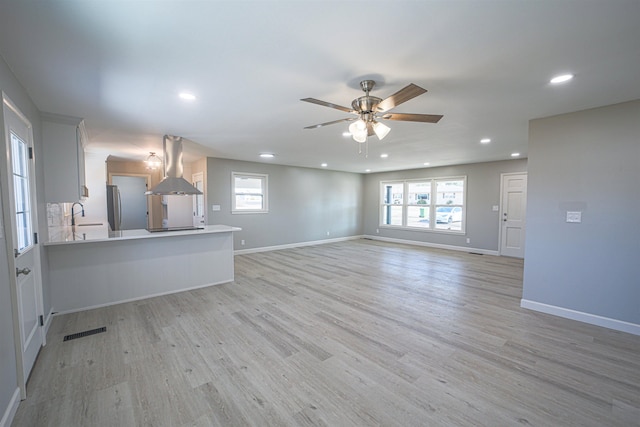 unfurnished living room with sink, plenty of natural light, light hardwood / wood-style floors, and ceiling fan