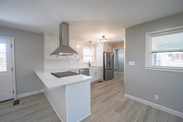 kitchen with backsplash, stainless steel appliances, island exhaust hood, decorative light fixtures, and kitchen peninsula