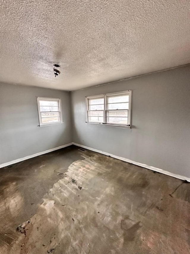 empty room with a textured ceiling and baseboards