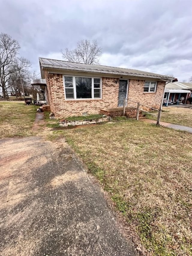 view of front of house with brick siding, metal roof, and a front lawn