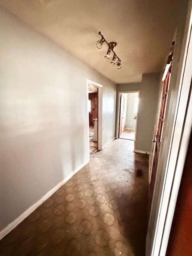 corridor featuring baseboards and concrete flooring