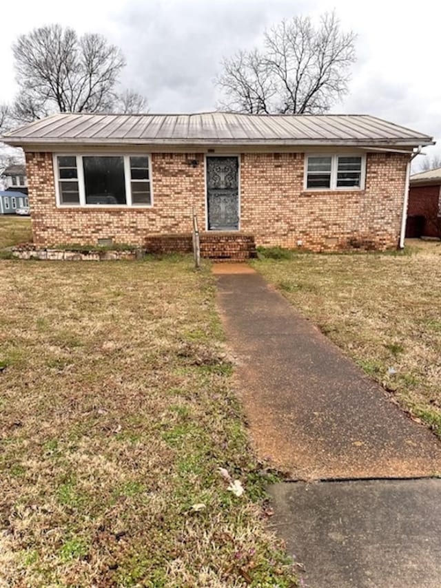 ranch-style home with a front yard, brick siding, metal roof, and entry steps