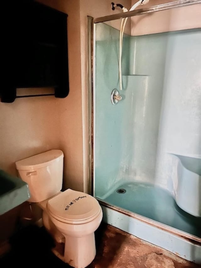 bathroom featuring a stall shower, concrete floors, and toilet