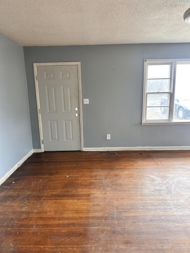 spare room with a textured ceiling, baseboards, and wood finished floors