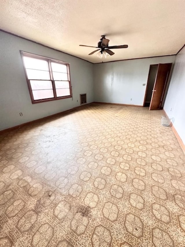 spare room featuring a textured ceiling, baseboards, and a ceiling fan