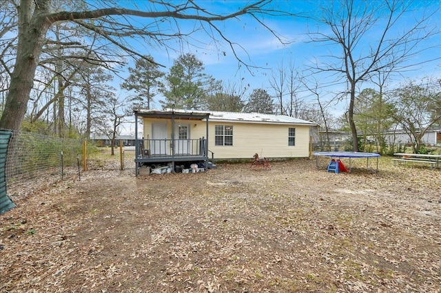  - back of property with a trampoline, a wooden deck, and a metal roof