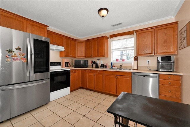  - kitchen with appliances with stainless steel finishes, under cabinet range hood, light countertops, light tile patterned floors, and brown cabinetry