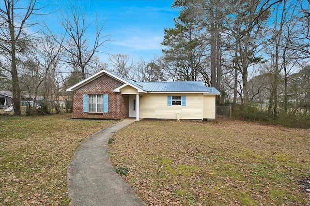  - view of front facade featuring a front yard, a metal roof, and brick siding
