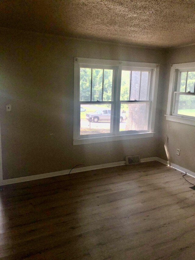  - empty room featuring dark wood-style floors, a textured ceiling, and baseboards