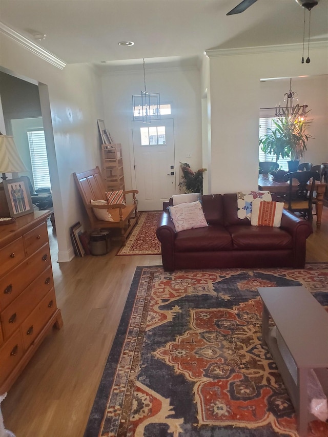 living room featuring hardwood / wood-style floors, a healthy amount of sunlight, ornamental molding, and an inviting chandelier