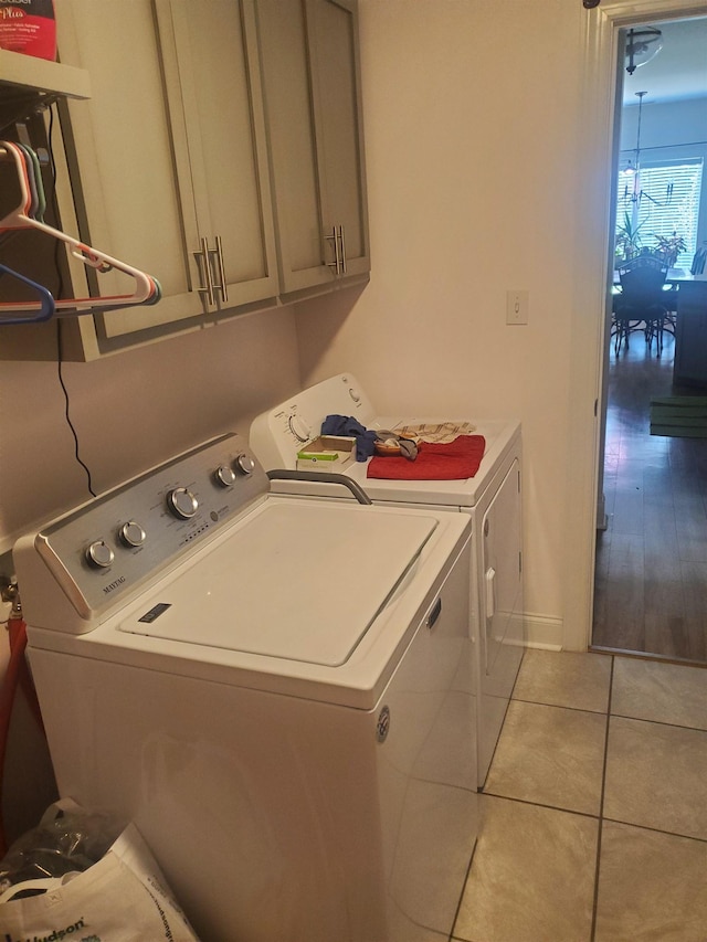 laundry area featuring separate washer and dryer, light tile patterned flooring, and cabinets