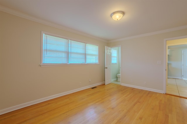 empty room featuring visible vents, light wood finished floors, baseboards, and ornamental molding